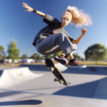 Eine junge Frau mit blondem Pferdeschwanz schwebt über ihrem Skateboard, während sie einen Trick in einem sonnigen Skatepark ausführt.