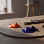 Eine Holzpalette mit einem Pinsel und frischer orangefarbener und blauer Farbe, die zum Malen bereitliegt.