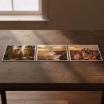 Drei Fotos liegen nebeneinander auf einem Holztisch, die von links nach rechts einen sonnigen Wald mit Lichtstrahlen, eine felsige Küstenlandschaft mit Leuchtturm bei Dämmerung und eine beleuchtete Stadt bei Nacht zeigen.