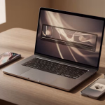 Ein Laptop zeigt ein Video auf seinem Bildschirm, umgeben von drei Smartphones auf einem Holztisch, der von Tageslicht erhellt wird.