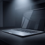 Ein modernes Laptop auf einem dunklen Schreibtisch, beleuchtet von einem Lichtkegel, der seine zentrale Rolle hervorhebt.